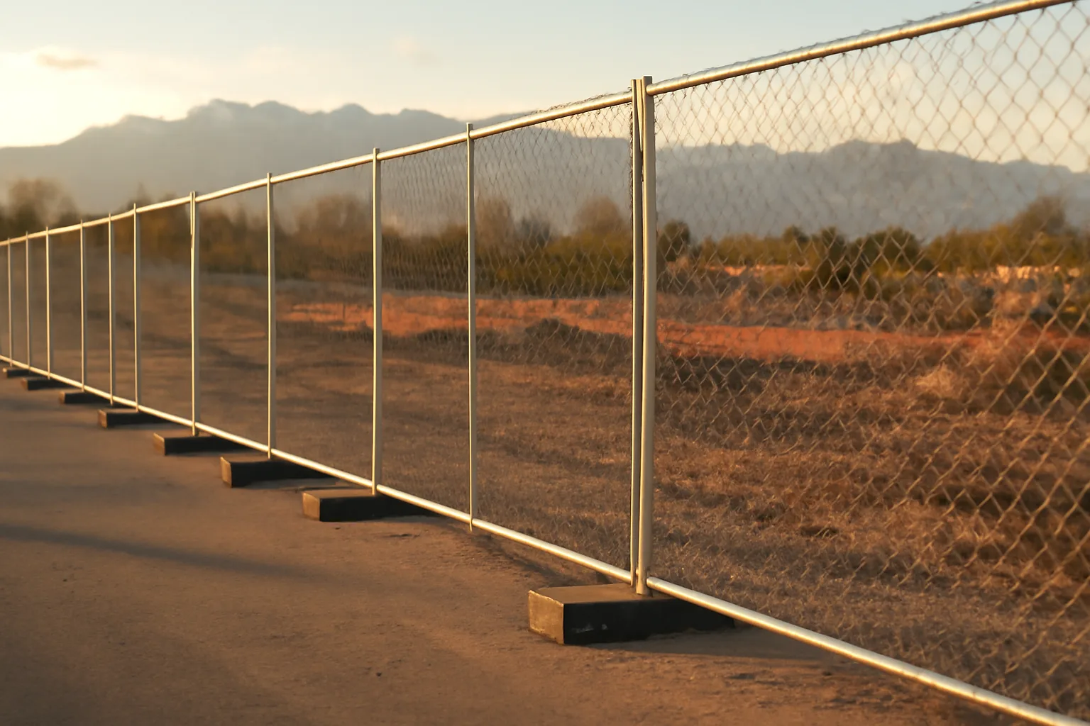 Temporary fence panels on a Utah construction site with mountains behind