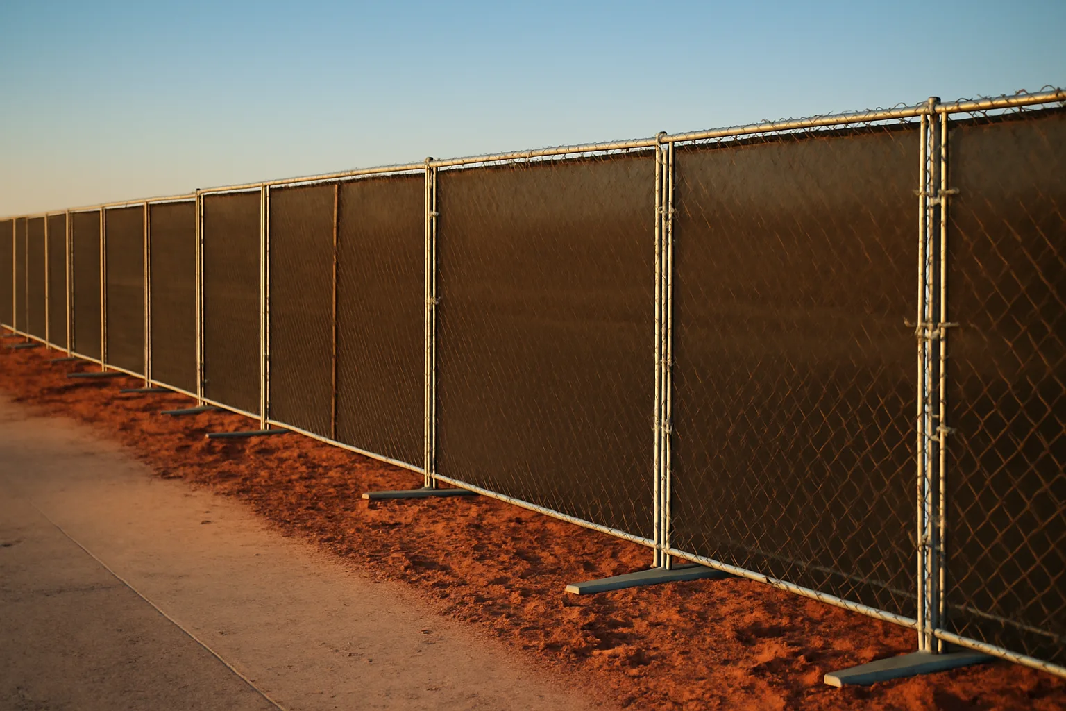 Temporary chain-link fence panels with windscreen along a Texas construction site perimeter